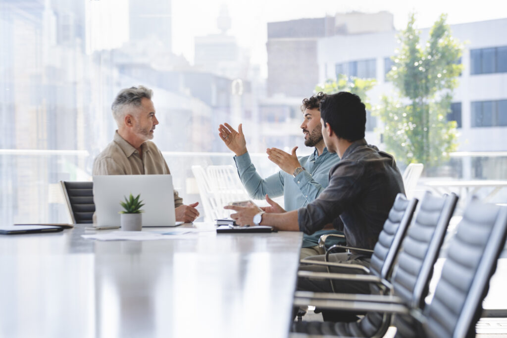 Three colleagues discussing their work around an office table.