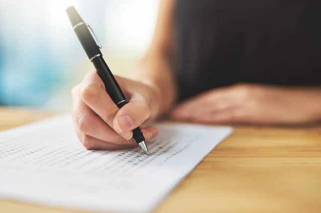 A person writing on a printed worksheet.