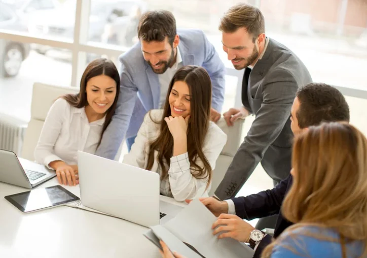 Colleagues working together around a laptop.