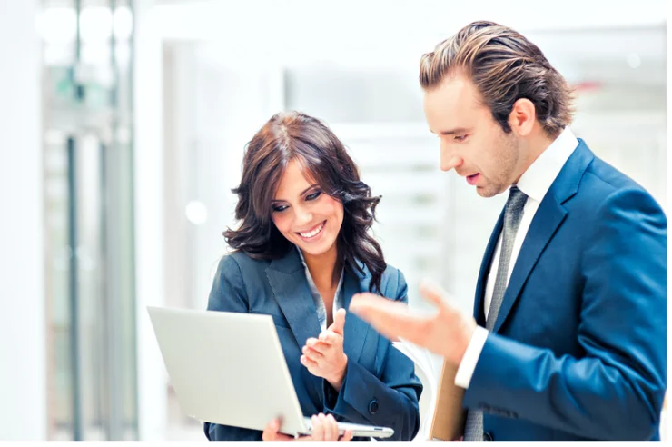 Two colleagues reviewing a laptop during a business conversation.
