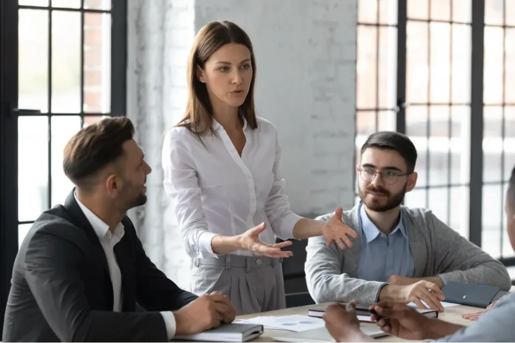 A woman leading a discussion with colleagues around a table.