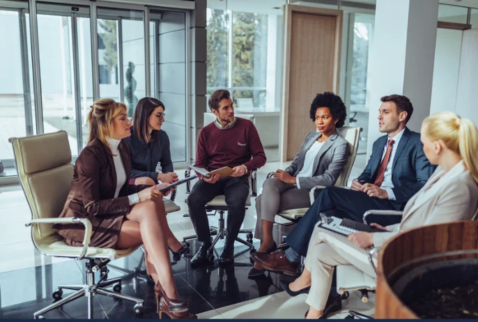 A small group sharing ideas in a circle of office chairs.